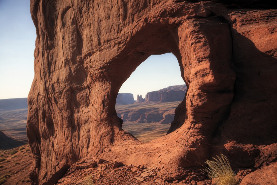 Ear of the Wind, a wind-carved sandstone arch opening in a red rock wall in the quiet Monument Valley backcountry