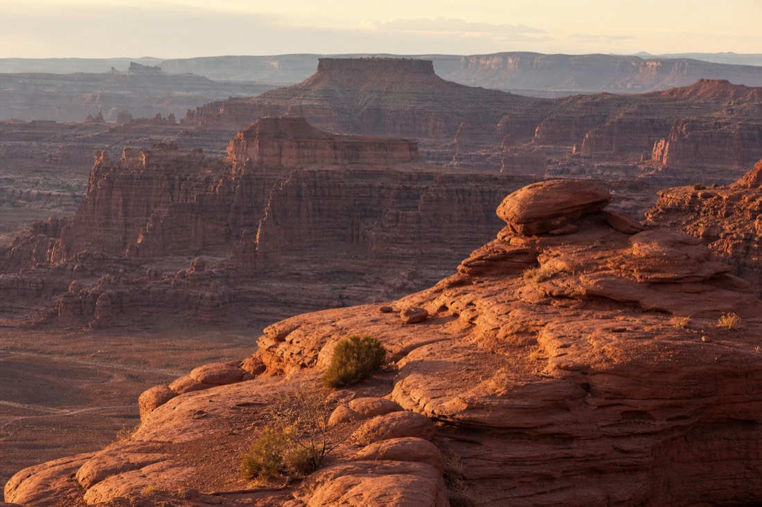 The John Ford Point promontory glowing in late afternoon light with layered red buttes receding into the distance
