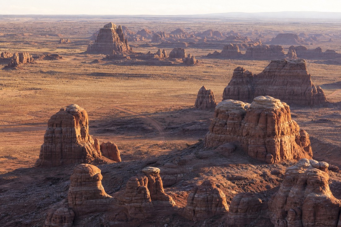 Layered sandstone buttes stretching to the horizon from Artist's Point across the open valley floor in warm afternoon light