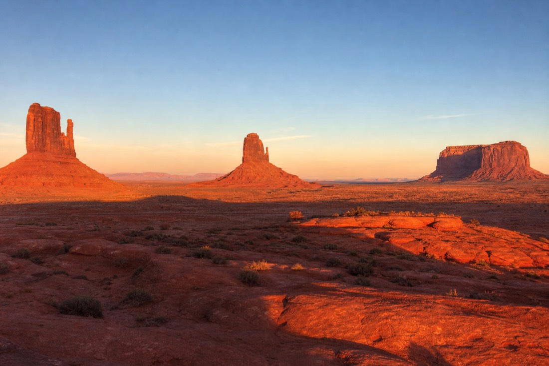 West Mitten, East Mitten and Merrick Butte lined up at sunrise with long shadows raking across the red sand