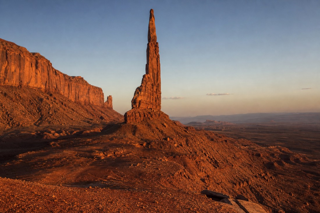 Warm evening light striking the slender Totem Pole spire and surrounding red dunes deep in the backcountry