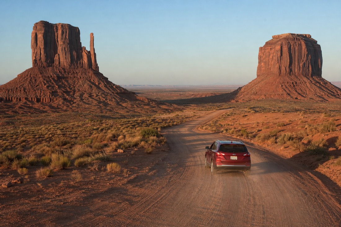 A car on the red dirt 17-mile loop road winding between the East and West Mitten buttes
