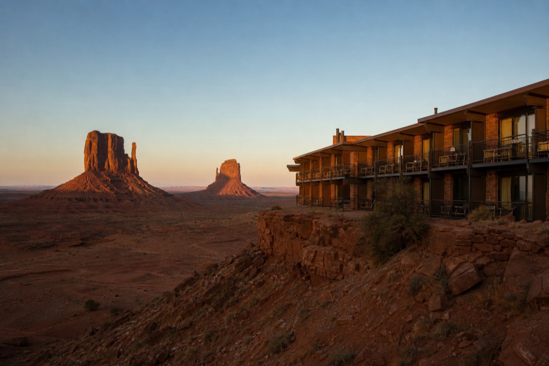 A mesa-top lodge silhouette with room balconies facing the two Mitten buttes catching first light, no branding
