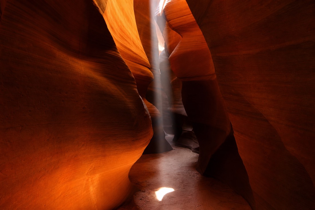 Glowing orange sandstone walls of an Antelope Canyon slot with a shaft of light