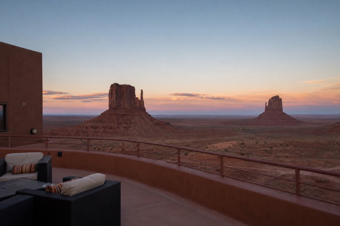 Hotel terrace at dusk framing the two Mitten buttes across the darkening desert