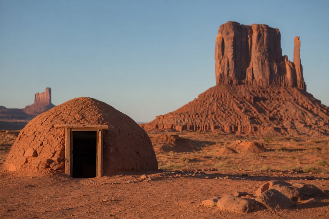 A traditional Navajo hogan sitting quietly on the red desert floor near buttes