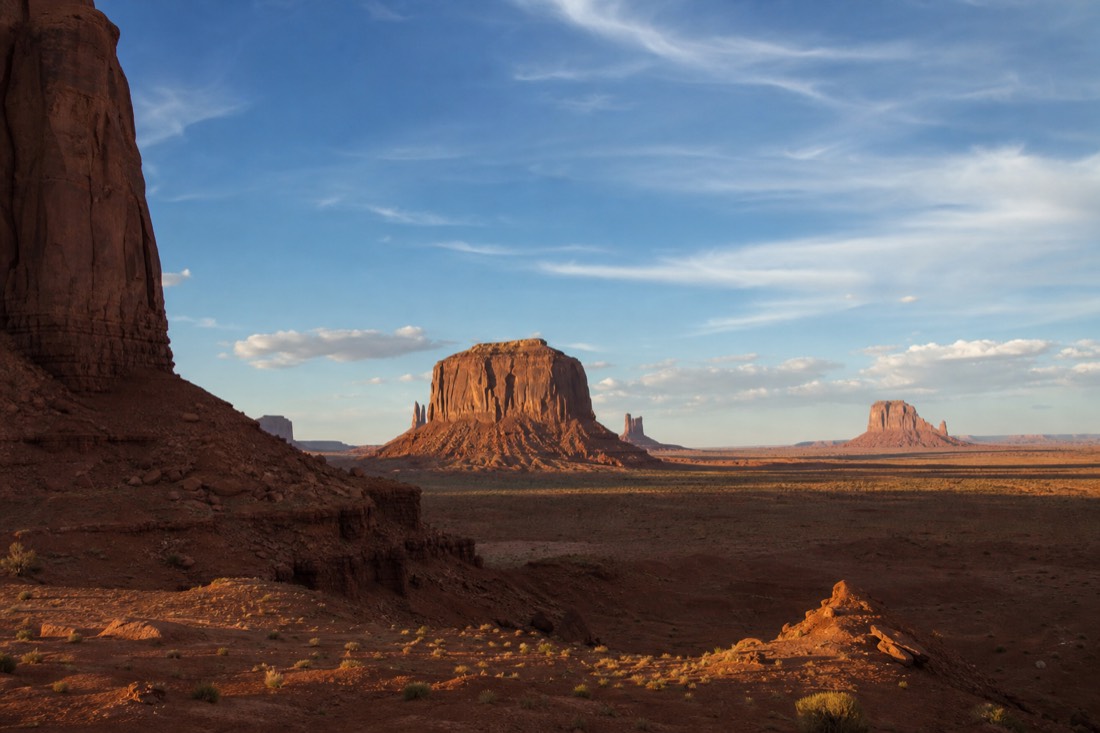 Late-afternoon light raking across the buttes as long shadows stretch over the sand